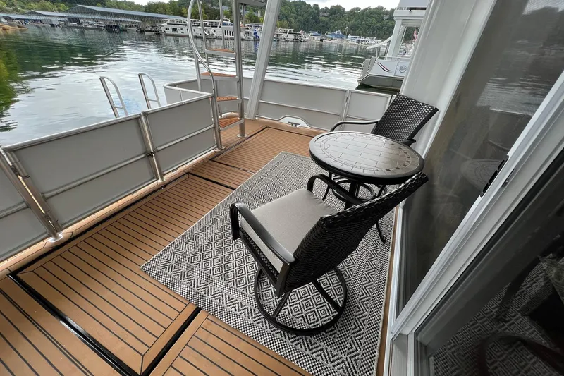 Slide: The Image of 2022 Trifecta houseboat deck with chairs, table, and scenic waterfront view. - 42