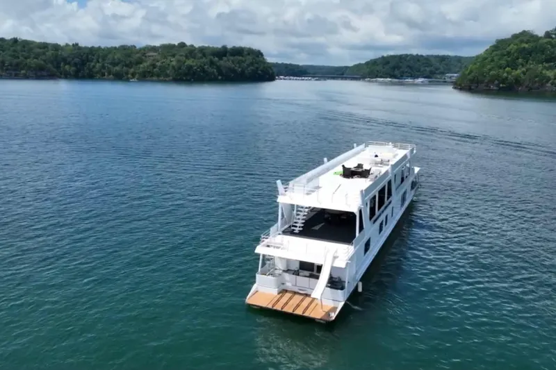 Slide: The Image of 2022 Trifecta HOUSEBOAT cruising on a serene lake with lush green islands. - 5