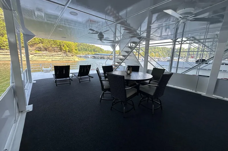 Slide: The Image of Spacious 2022 Trifecta houseboat deck with seating, overlooking serene water and lush shoreline. - 57