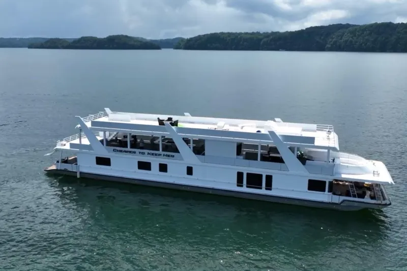 Slide: The Image of 2022 Trifecta HOUSEBOAT on serene lake with lush green islands in the background. - 6