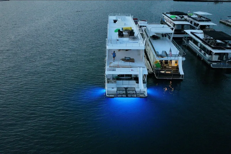 Slide: The Image of Aerial view of 2022 Trifecta houseboat with blue underwater lights at dusk. - 7