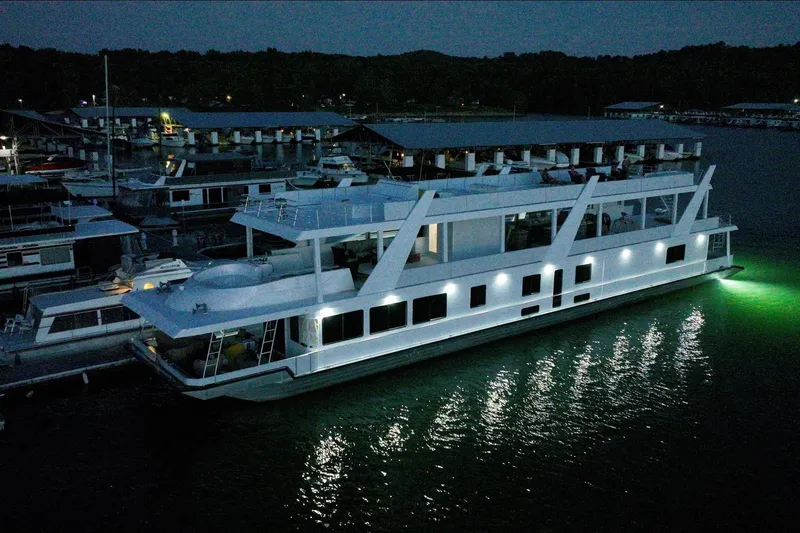 Slide: The Image of Modern 2022 Trifecta houseboat illuminated at night, docked in a serene marina setting. - 8