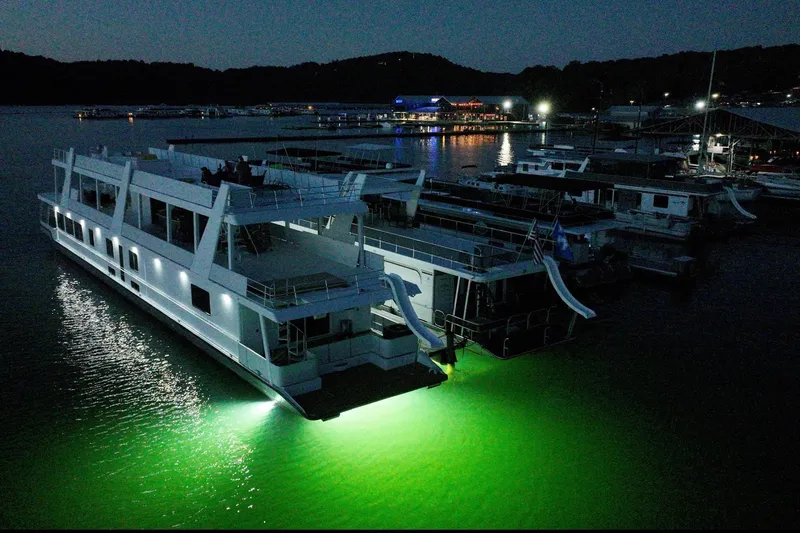 Slide: The Image of 2022 Trifecta houseboat illuminated at night, docked with other boats. - 9