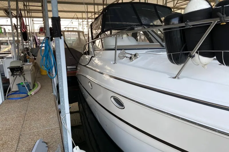 Slide: The Image of 2004 Larson Cabrio 330 docked in a marina, featuring sleek white design and protective fenders. - 2