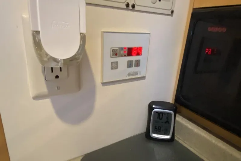 Slide: The Image of Control panel and digital thermometer inside a 2004 Larson Cabrio 330 boat cabin. - 24