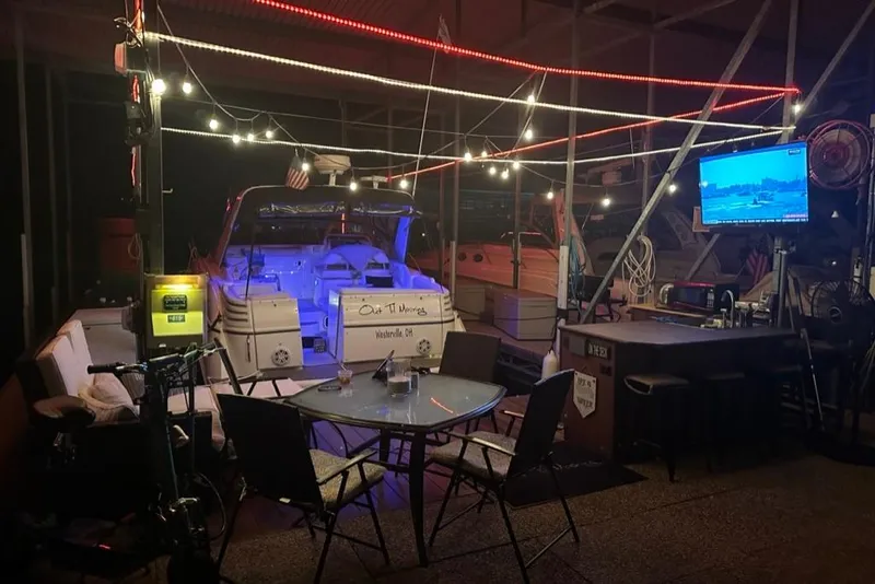 Slide: The Image of Outdoor seating area with a 2004 Larson Cabrio 330 boat, string lights, and a TV screen. - 32