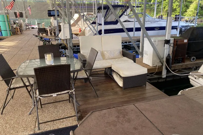 Slide: The Image of Dockside seating area with wicker furniture near a 2004 Larson Cabrio 330 boat. - 34