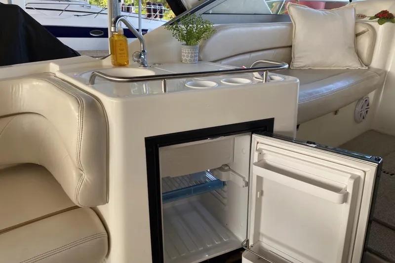 Slide: The Image of 2004 Larson Cabrio 330 interior with open mini fridge, sink, and seating area. - 4