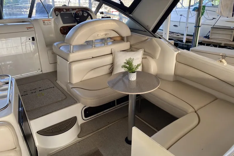 Slide: The Image of 2004 Larson Cabrio 330 boat interior with beige seating and small table. - 6