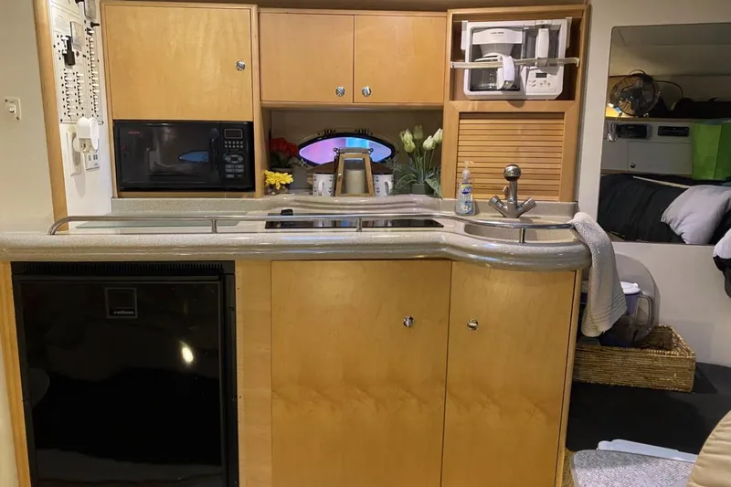 Slide: The Image of 2004 Larson Cabrio 330 boat interior with kitchenette, featuring microwave, sink, and storage cabinets. - 9