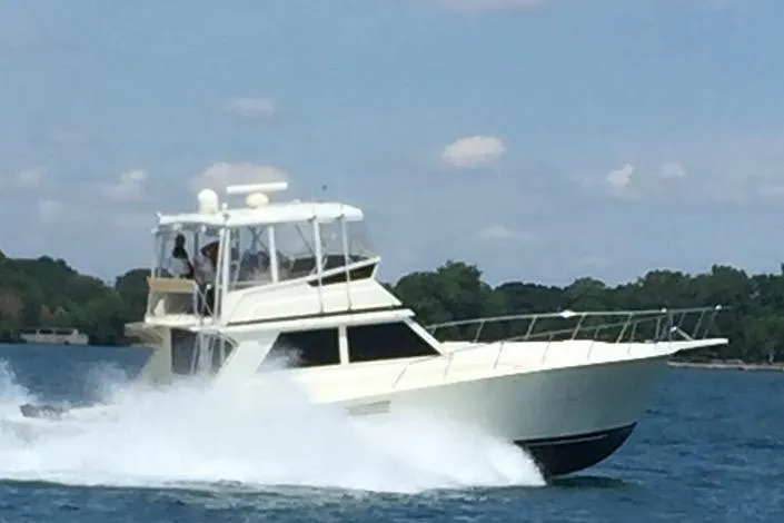 The Image of 1988 Viking 48 Convertible yacht cruising on a lake with trees in the background. - 0