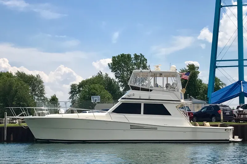 Slide: The Image of 1988 Viking 48 Convertible yacht docked by a waterfront, under a clear blue sky. - 1