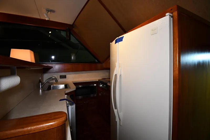 Slide: The Image of 1988 Viking 48 Convertible yacht kitchen with sink, refrigerator, and wooden cabinetry. - 54