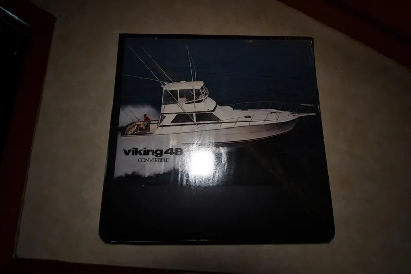 Slide: The Image of 1988 Viking 48 Convertible boat brochure on a table surface. - 84
