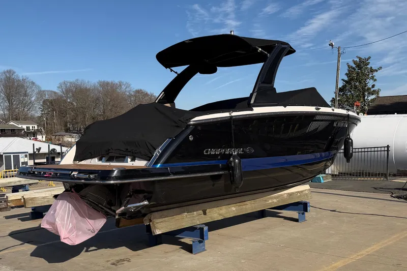 Slide: The Image of 2018 Chaparral 267 SSX boat on dry dock, covered, under clear blue sky. - 3