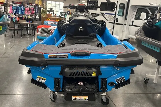 Slide: The Image of A blue Sea-Doo jet ski is in a showroom, surrounded by other vehicles and equipment. - 4