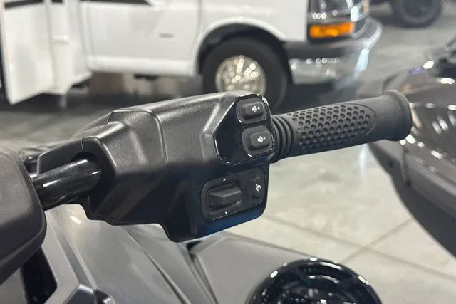 Slide: The Image of Close-up of a black handlebar grip with control buttons, a white van in the background. - 33