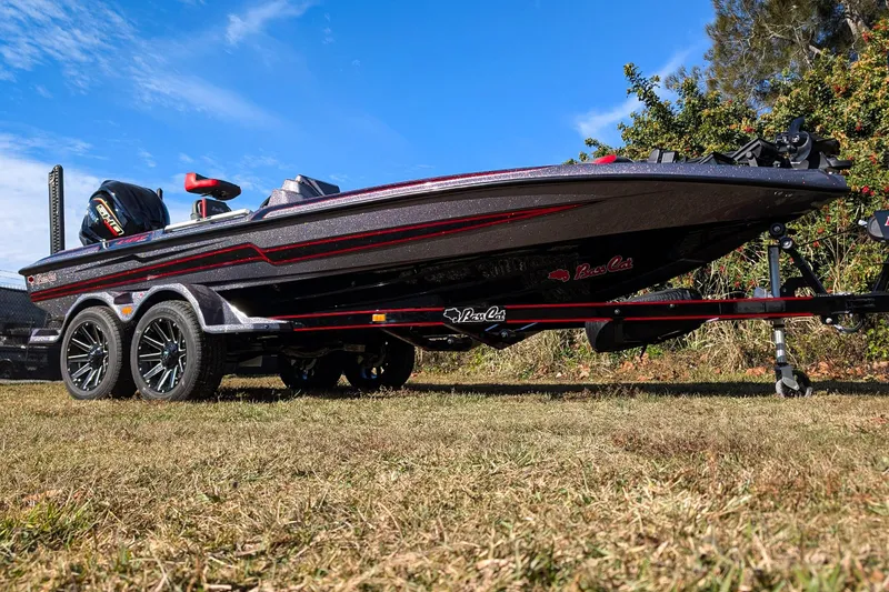 The Image of 2026 Bass Cat Lynx STS boat on trailer, parked on grass with lush greenery background. - 0