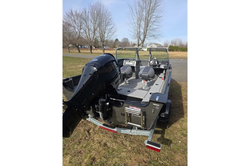 Slide: The Image of 2026 Alumacraft Classic 165 Sport boat with outboard motor, parked on grass. - 2