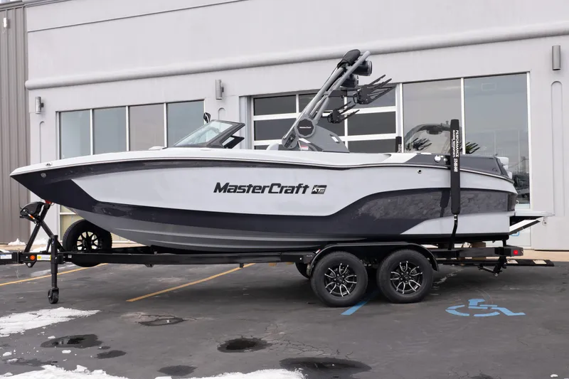 Slide: The Image of 2026 MasterCraft XT22 boat on trailer, parked outside a building. - 2