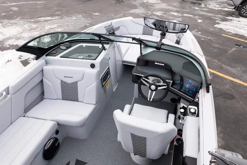 Slide: The Image of 2026 MasterCraft XT22 boat interior with modern dashboard and seating, parked on snowy pavement. - 20