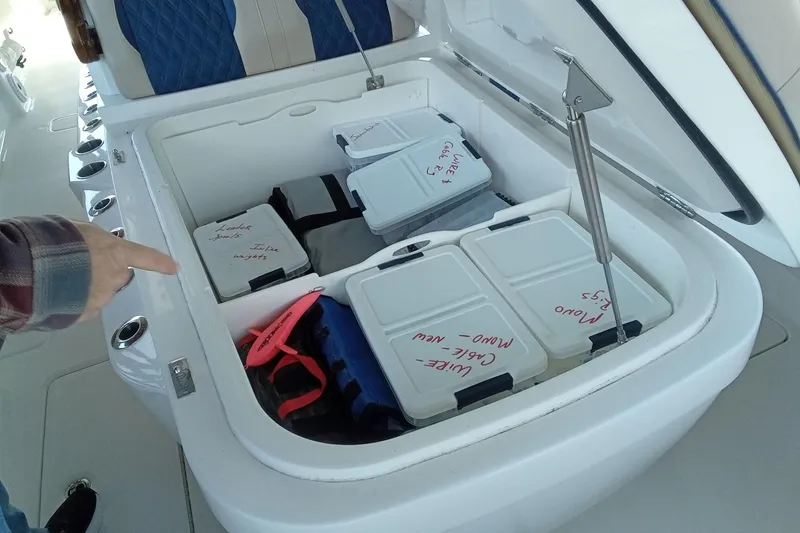 Slide: The Image of Storage compartment on 2022 Invincible 39 Open Fisherman, organized with labeled containers and gear. - 25