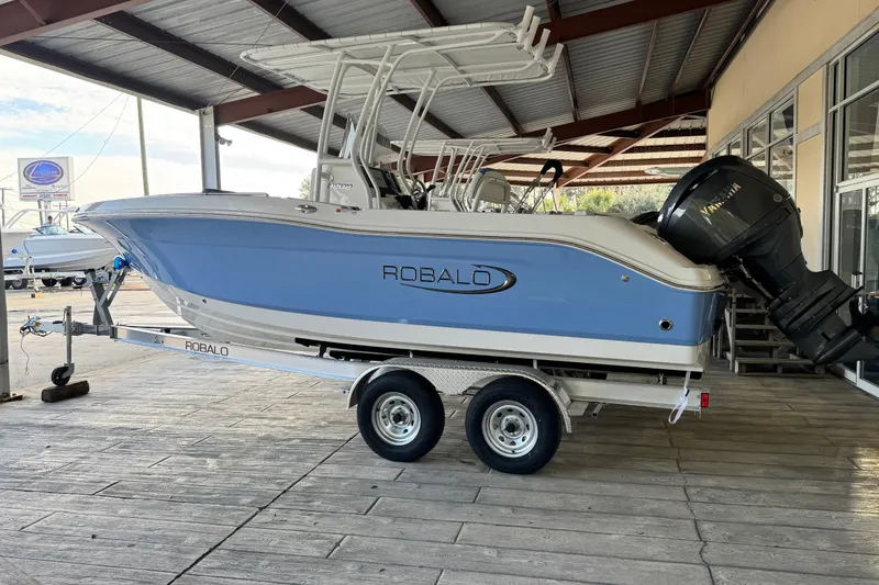 Slide: The Image of 2026 Robalo R202 Explorer boat on trailer, under a metal roof. - 2