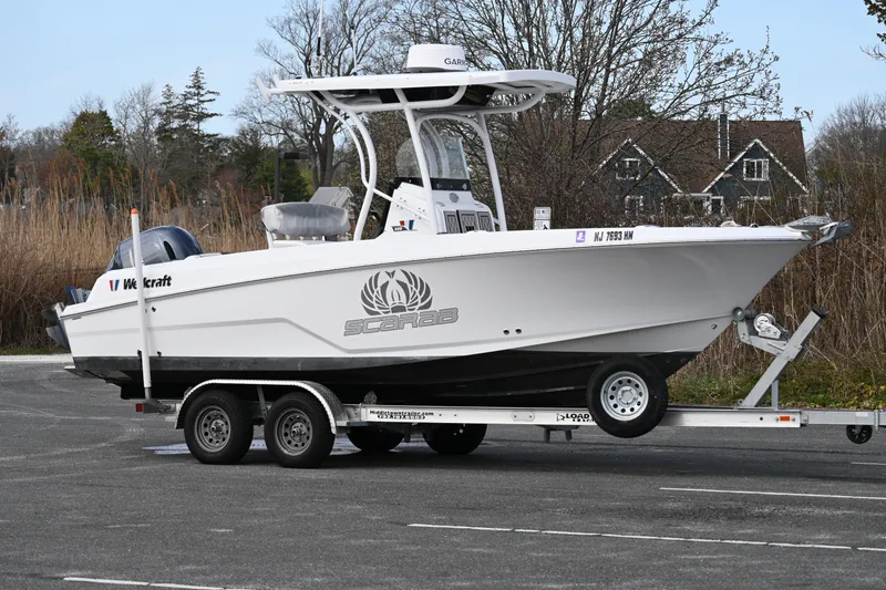 Slide: The Image of 2020 Wellcraft 222 Fisherman boat on trailer, parked outdoors near trees and houses. - 12