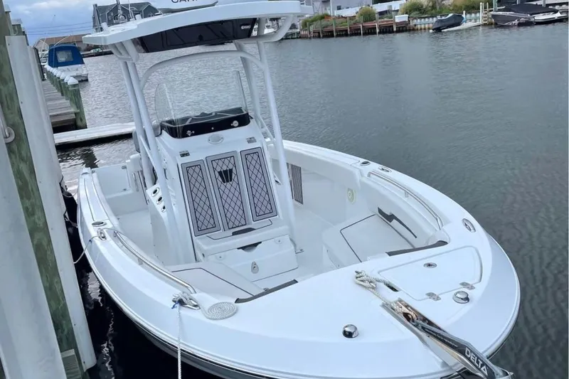 Slide: The Image of 2020 Wellcraft 220 Fisherman boat docked in a marina, featuring sleek white design. - 2