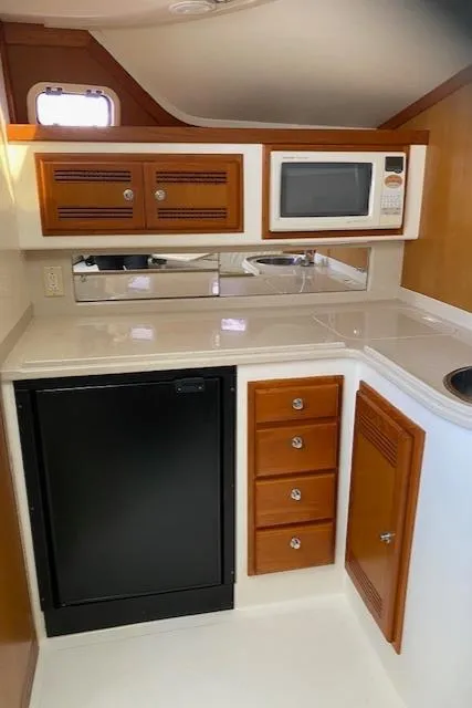 Slide: The Image of Compact kitchen area in a 2000 Cabo 35 Express boat with microwave and mini-fridge. - 30