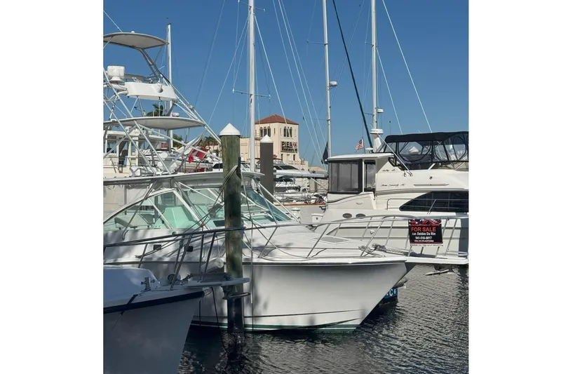 Slide: The Image of 2000 Cabo 35 Express boat docked, for sale sign visible, marina background. - 5