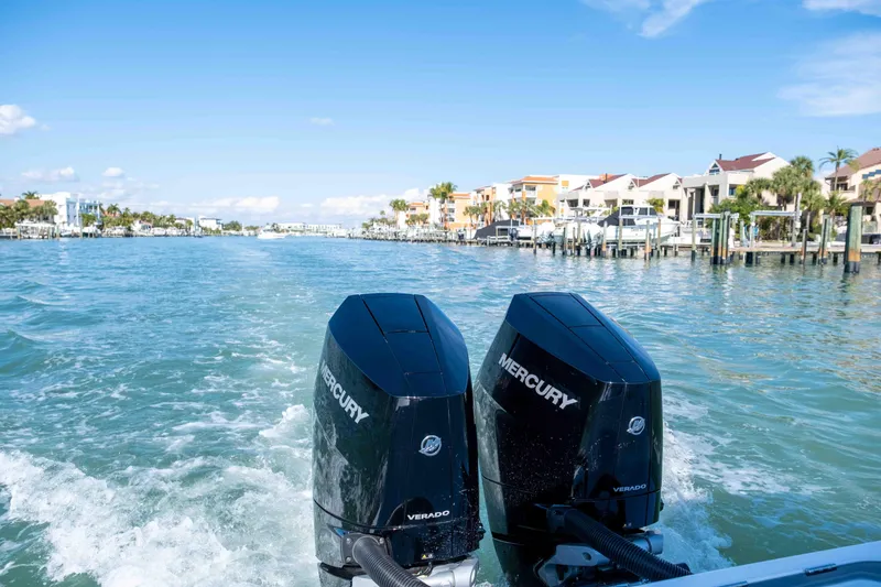 Slide: The Image of Twin Mercury outboard engines on a 2026 Reef Runner 340 boat cruising through a scenic waterway. - 3