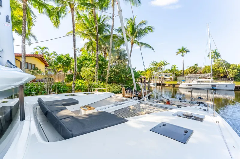 Slide: The Image of 2024 Lagoon 51 yacht docked in tropical marina with palm trees and clear sky. - 11