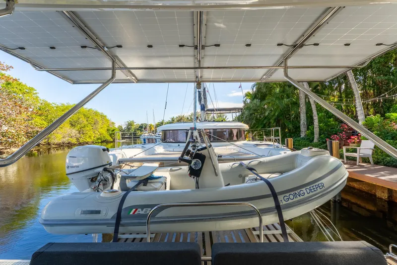 Slide: The Image of 2024 Lagoon 51 yacht with dinghy, docked in a lush, tropical setting. - 29