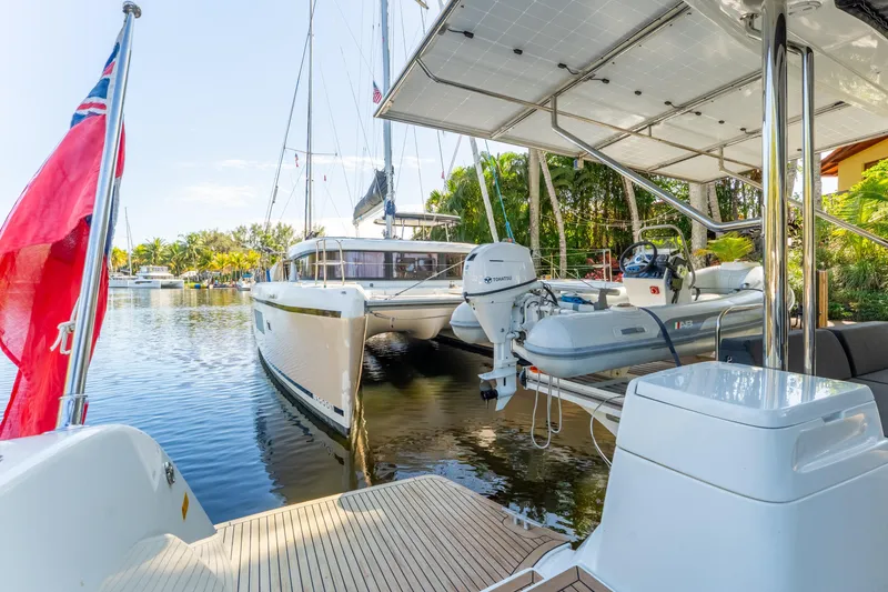 Slide: The Image of 2024 Lagoon 51 catamaran docked with inflatable boat and lush surroundings. - 30