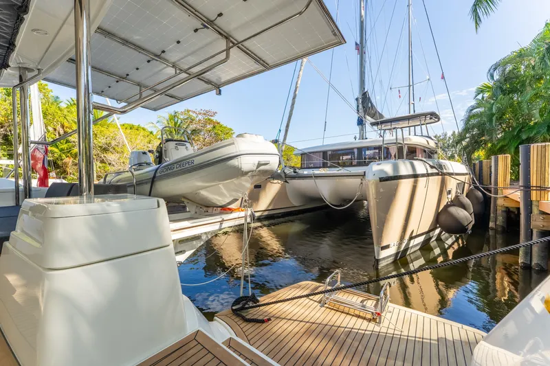 Slide: The Image of 2024 Lagoon 51 catamaran docked with tender boat, surrounded by lush greenery. - 31