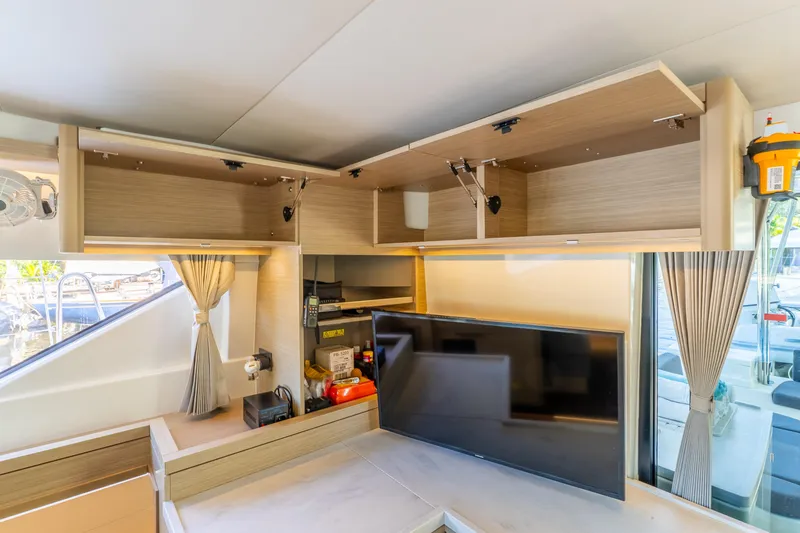 Slide: The Image of 2024 Lagoon 51 yacht interior with open cabinets and modern TV setup. - 42
