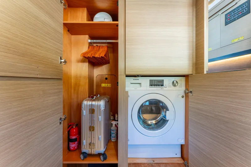Slide: The Image of Laundry area in 2024 Lagoon 51 yacht with washing machine, storage, and suitcase. - 61
