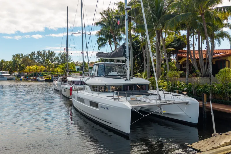 Slide: The Image of 2024 Lagoon 51 catamaran docked by tropical waterfront with palm trees. - 7