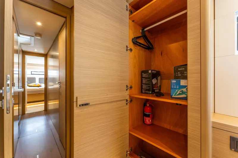 Slide: The Image of 2024 Lagoon 51 yacht interior with open closet, fire extinguisher, and hallway view. - 74