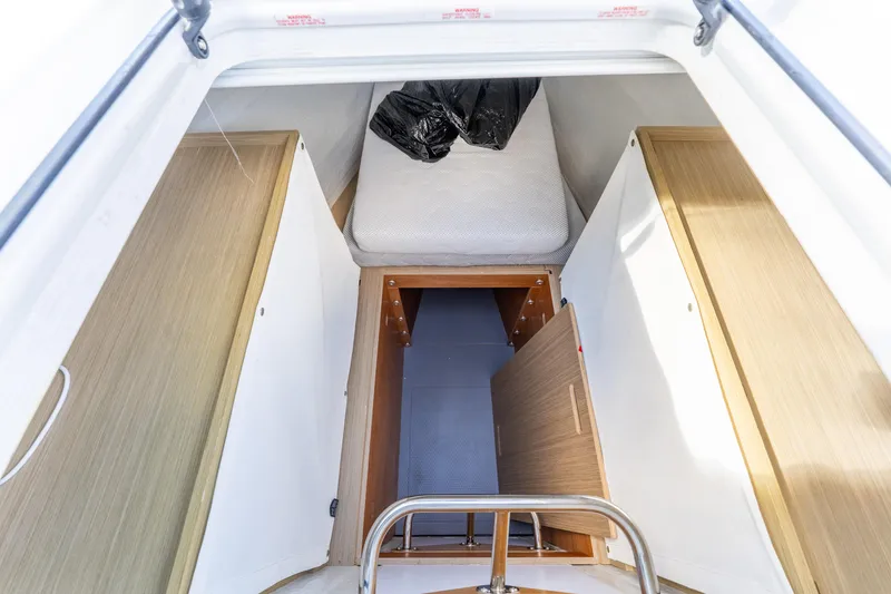 Slide: The Image of 2024 Lagoon 51 yacht interior cabin with wooden finishes and compact bed space. - 78