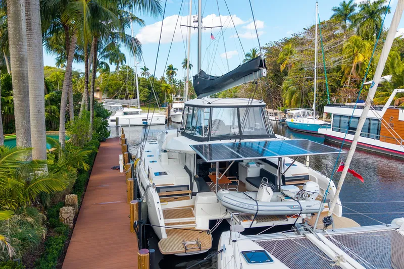 Slide: The Image of 2024 Lagoon 51 yacht docked in tropical marina with lush palm trees. - 87