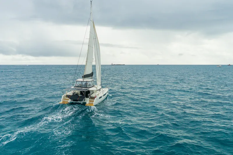 Slide: The Image of 2024 Lagoon 51 catamaran sailing on open sea with distant shoreline. - 88