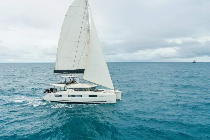 Slide: The Image of 2024 Lagoon 51 sailing catamaran on open sea under cloudy skies. - 90