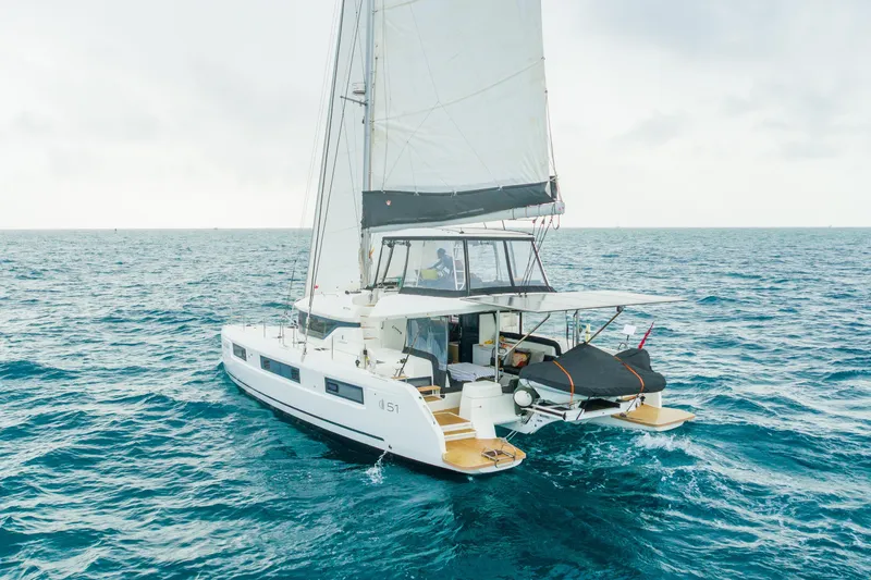 Slide: The Image of 2024 Lagoon 51 sailing catamaran cruising on open turquoise sea under cloudy sky. - 97