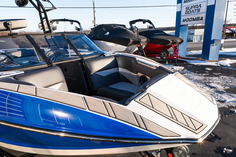 Slide: The Image of 2021 Moomba Mondo boat with blue and white design, displayed outdoors in a dealership. - 10