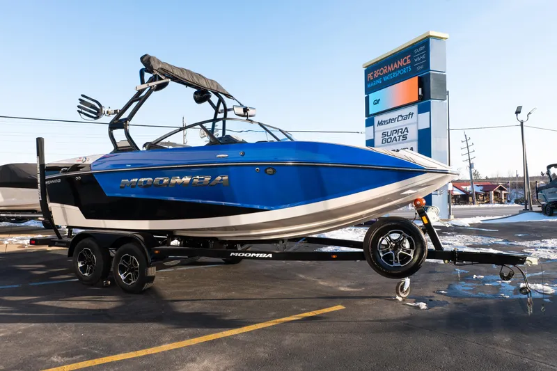 Slide: The Image of 2021 Moomba Mondo boat on trailer at dealership, showcasing sleek design and vibrant blue color. - 8