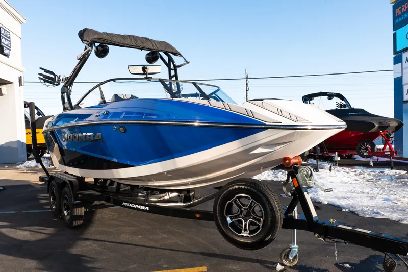 Slide: The Image of 2021 Moomba Mondo boat on trailer, blue and white design, parked outdoors. - 9