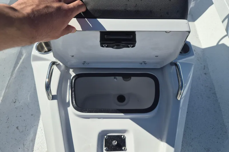 Slide: The Image of Open storage compartment on 2026 Xpress H20B Bay boat with hand lifting lid. - 9