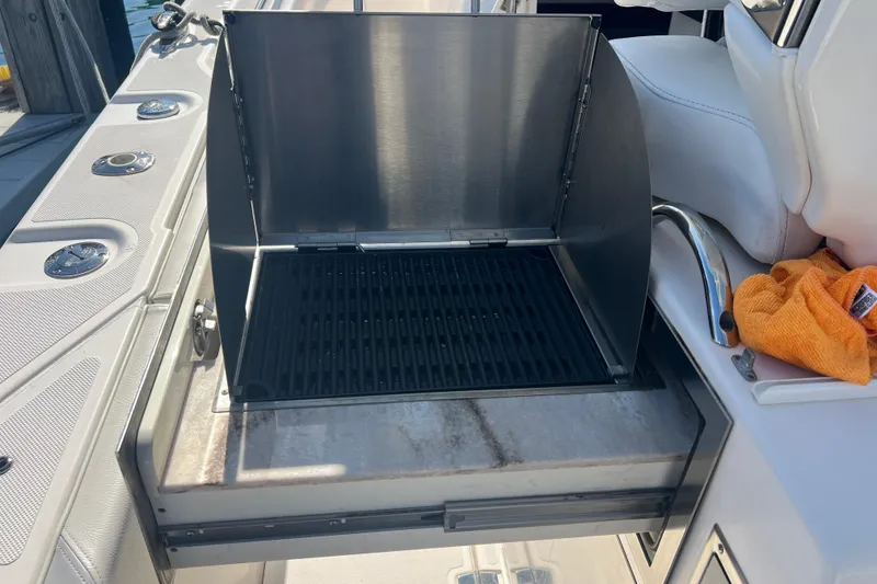 Slide: The Image of Built-in grill on 2019 Pursuit S 368 Sport boat, open lid, docked setting. - 17